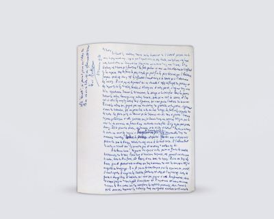 un livre ouvert, sur lequel figurent des inscriptions en bleu, posé sur une surface blanche