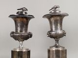 deux vases en argent posés l'un à côté de l'autre sur une table
