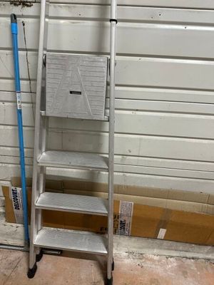 a ladder that is leaning against a wall next to a broom