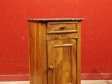 une petite armoire en bois posée au sol, avec un plateau en marbre