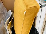 a yellow pillow sitting on top of a chair in the corner of a room
