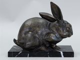 statue of a rabbit sitting on a marble base on a white background