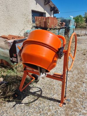 an orange cement mixer sitting in front of a building