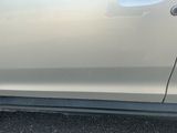 une voiture blanche dont la poignée de porte est cassée, garée sur le bord de la route