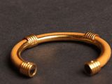 a close up of a gold bracelet on a black surface