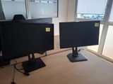 two monitors sitting on a desk in front of a window