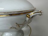 a white bowl with gold trim on top of a stack of plates