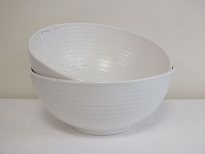 un bol blanc posé sur une table, avec une cuillère à l'intérieur