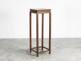 a small wooden table with a marble top on a concrete floor