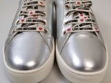 silver sneakers with love moschs on them on a white surface