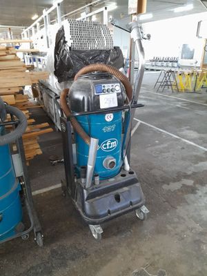 a blue machine that is sitting next to a pile of wood
