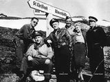 black and white photo of a group of men standing next to a sign