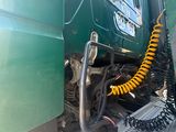 a green truck with a yellow hose attached to the back of it