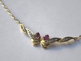 a close up of a gold necklace with a pink stone on it