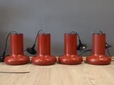 quatre lampes rouges posées sur un plancher en bois, près d'un mur