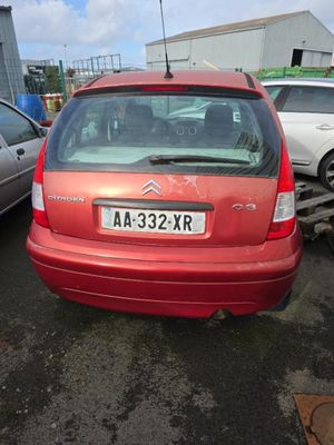 une voiture rouge garée sur un parking avec d'autres voitures