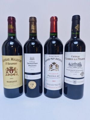 quatre bouteilles de vin sont alignées sur une surface blanche