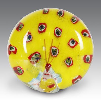 an image of a yellow glass paperweight with red and green eyes on it