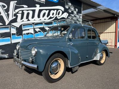 une voiture bleue garée devant un immeuble sur lequel est accrochée une pancarte