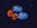 two orange and blue glass buttons sitting on top of a black surface