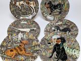 four plates with dogs on them sitting on a white surface