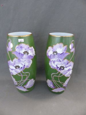 une paire de vases verts ornés de fleurs violettes, posés sur un fond gris