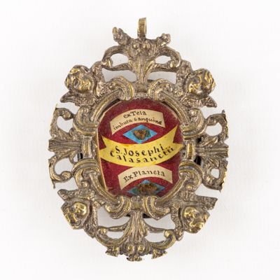 an image of a gold and red broochle with a ribbon around it