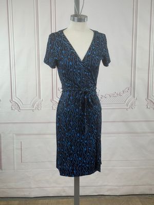 blue and black dress on a mannequin stand in front of a white wall