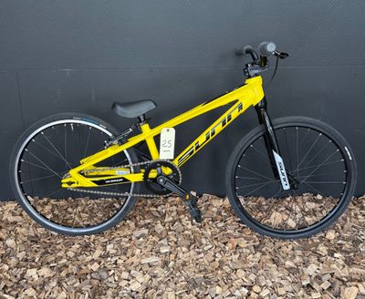 un vélo jaune garé contre un mur, posé à même le sol