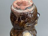 a brown vase with a red top sitting on top of a table