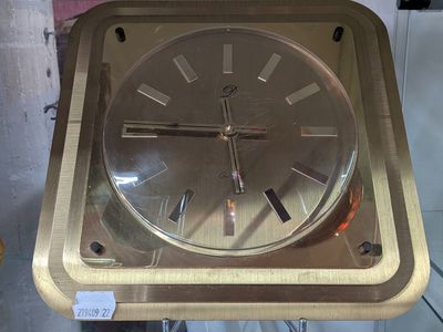 une horloge en or posée sur un socle en métal