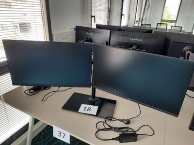 deux écrans posés sur un bureau devant une fenêtre