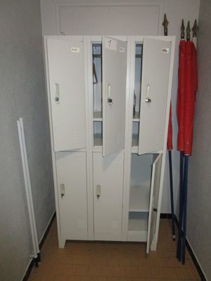 un placard dans un coin d'une pièce, avec une serviette rouge accrochée à la porte