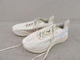 une paire de baskets blanches à lacets posées sur une surface grise