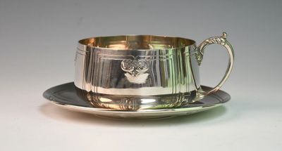 silverplated tea cup and saucer on a saucer on a white surface