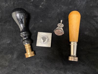 a close up of a wooden handle and a metal stamp on a black surface