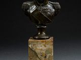 buste en bronze d'un homme posé sur un socle en marbre, sur fond noir
