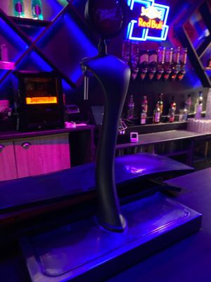 un bar avec un comptoir et des enseignes au néon accrochées au mur