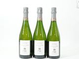 trois bouteilles de vin posées les unes à côté des autres sur une surface blanche