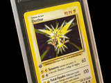 La carte Pokémon se trouve dans un étui en plastique transparent sur fond noir.