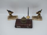 trois figurines d'oiseaux en laiton vieilli posées sur des socles en marbre, accompagnées d'une bougie