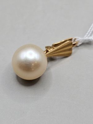 collier composé d'une perle blanche et d'une chaîne en or sur un fond gris