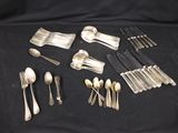 a lot of silverware on a black table cloth