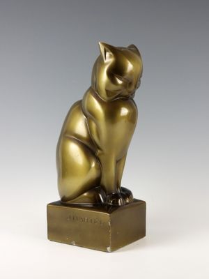 an image of a bronze cat statue sitting on top of a wooden block