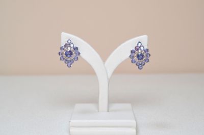 purple crystal earrings on a white stand on a white surface