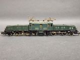a green train on the tracks on a gray surface