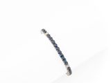a close up of a blue sapphire and diamond bracelet on a white surface
