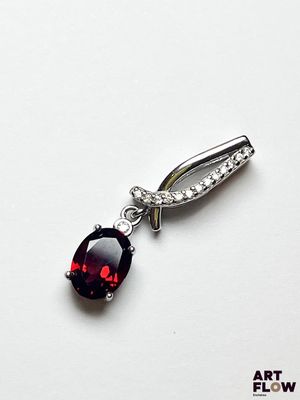 Gros plan sur un pendentif en pierre rouge et diamants posé sur une surface blanche