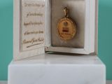 une petite boîte blanche contenant une médaille d'or