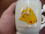 a person holding a coffee cup with a pikachu on it